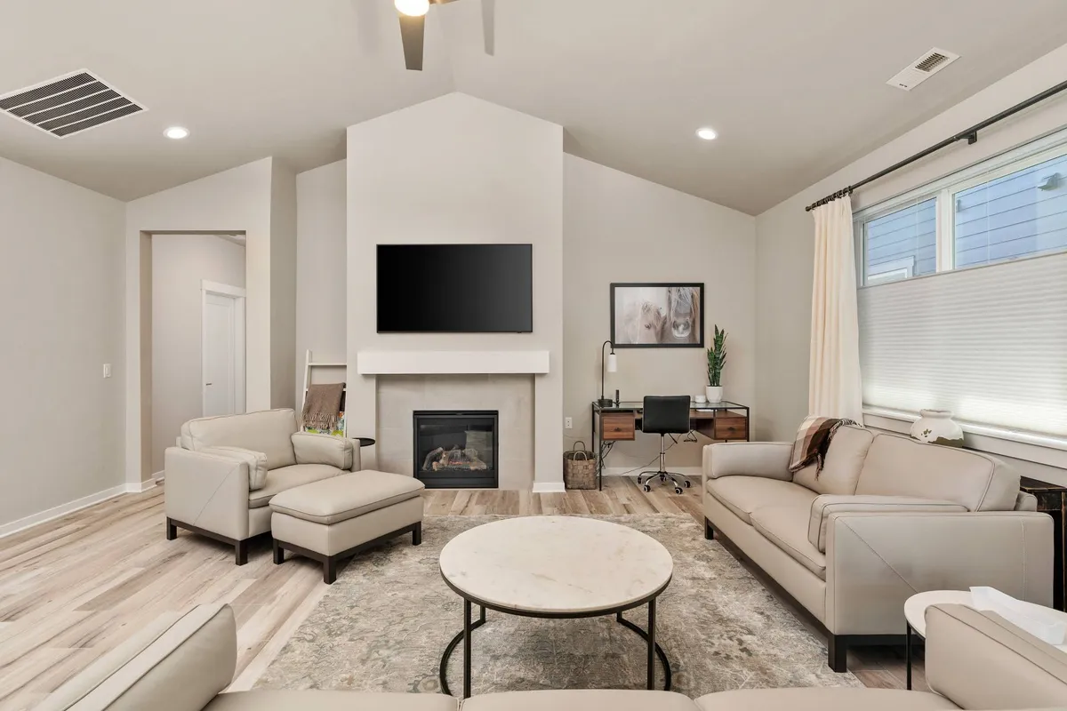 The image showcases a stylish, modern living room with a cozy gas fireplace as the centerpiece, surrounded by a comfortable sofa set and a sleek coffee table. Natural light fills the space, highlighting elegant furnishings and an inviting atmosphere perfect for relaxation or social gatherings.