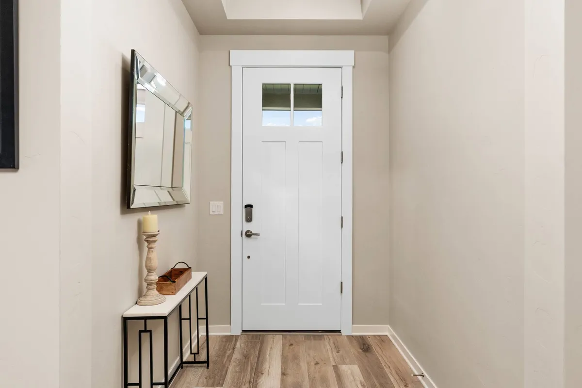 The image shows the home's front door, accompanied by a mirror and a stylish console table. The scene is well-lit and welcoming, signaling the invitation for guests to enter and gather. The entryway sets the tone for shared group experiences and memorable arrivals.