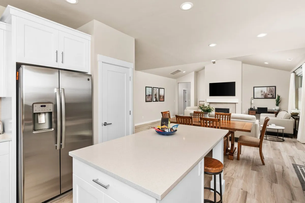 An open-concept interior featuring a kitchen island, dining table, and a cozy living area with a couch. The layout emphasizes spaciousness and functionality for daily living, gathering, and organizing belongings.