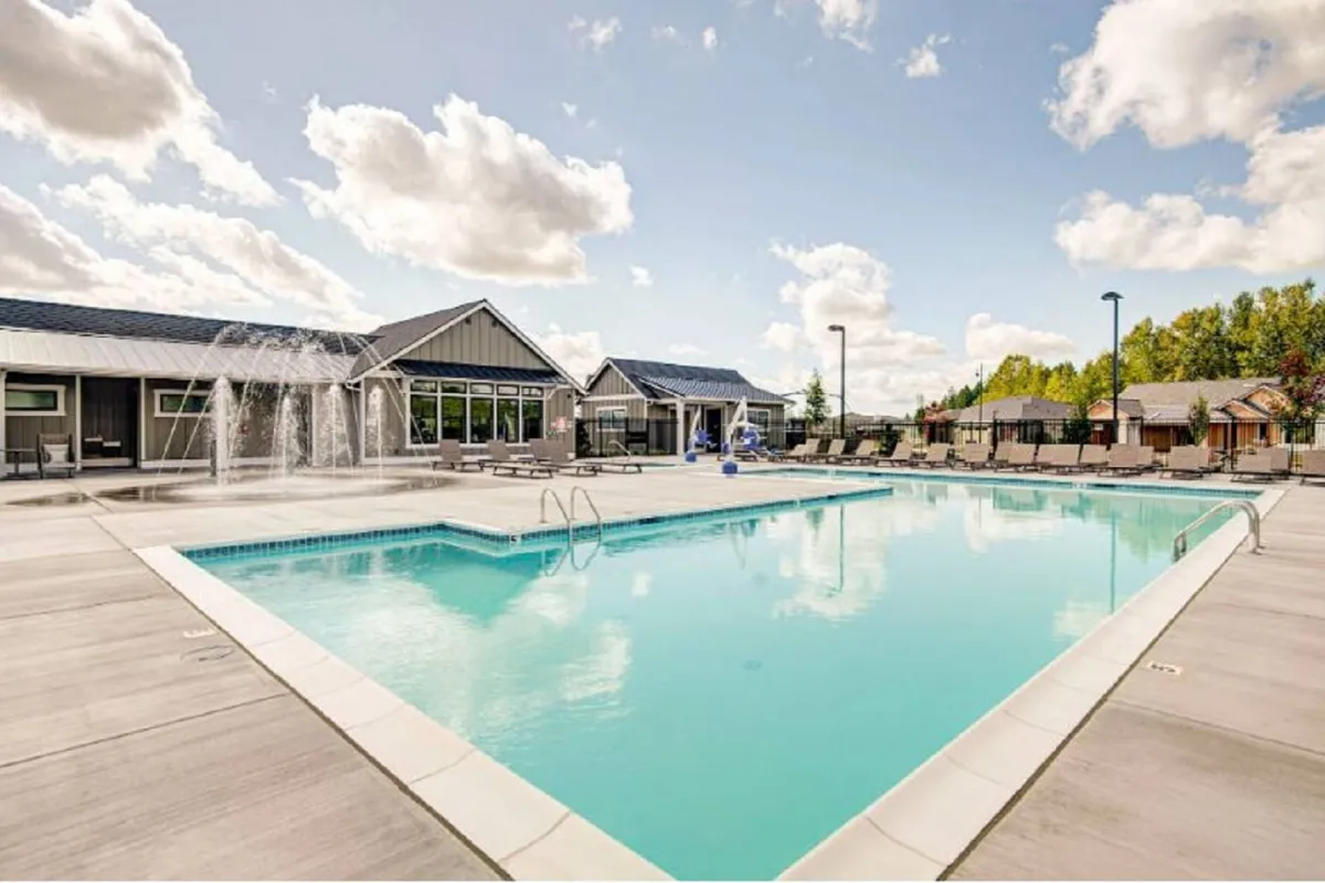 A vibrant exterior image showcasing the community's swimming pool surrounded by poolside chairs and a clubhouse. The scene is lively yet relaxing, with ample space for both sunbathing and socializing. Water features and comfortable seating create a welcoming atmosphere for families.