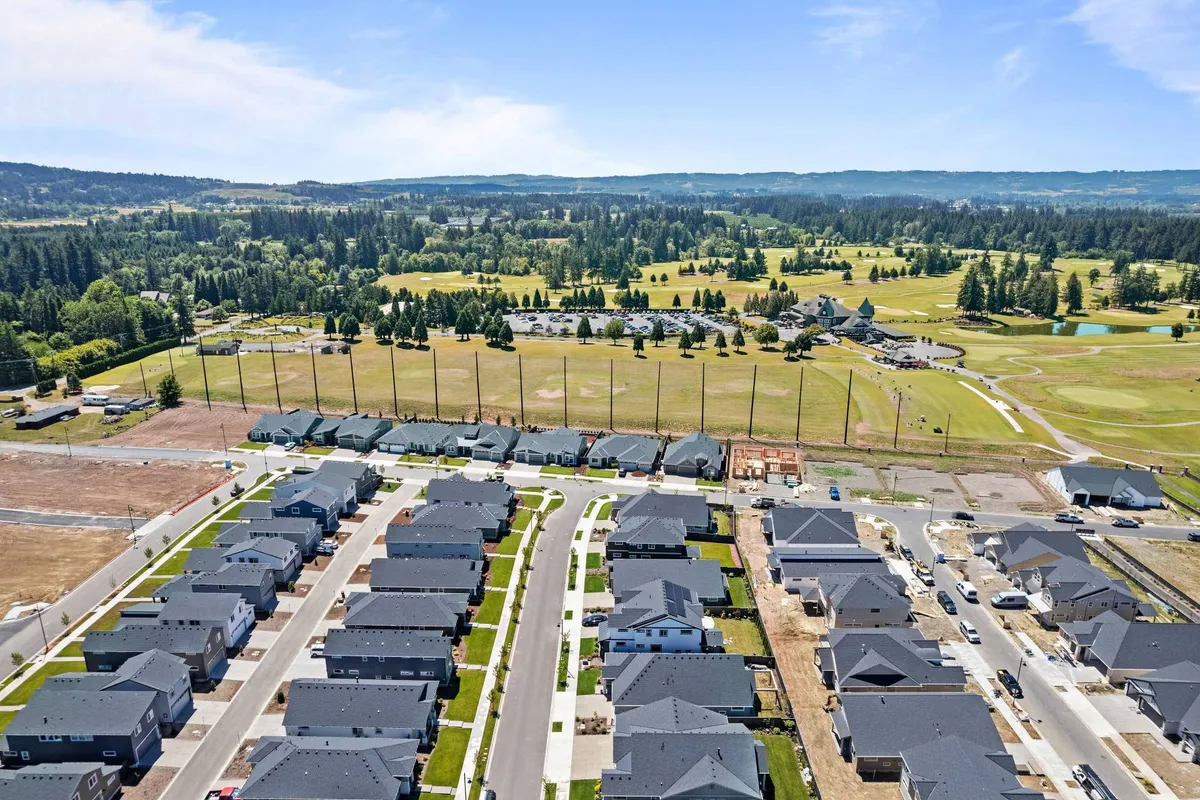 A panoramic exterior view of residential homes nestled beside a lush golf course, with green fields and mature trees, highlighting the community’s scenic walking paths and proximity to golf.